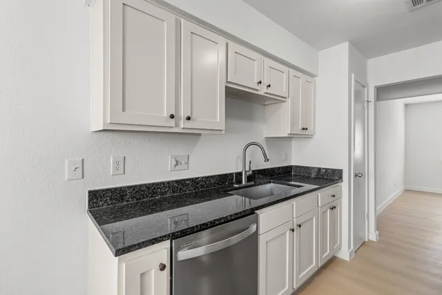 a kitchen with granite countertop white cabinets and sink