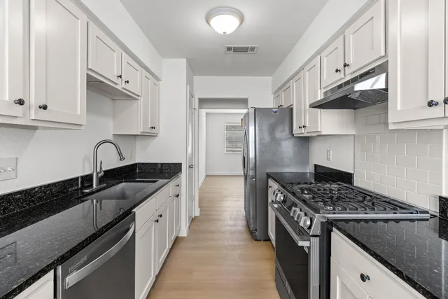 a kitchen with stainless steel appliances granite countertop a sink stove and cabinets