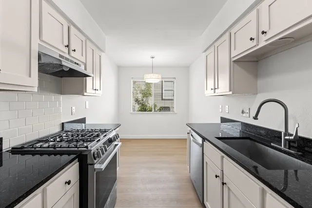 a kitchen with granite countertop a sink stove and cabinets
