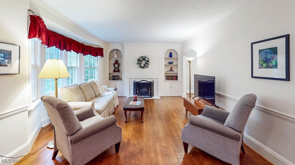 Living room featuring hardwood floors, fireplace with built ins on both sides, and ornamental crown molding.