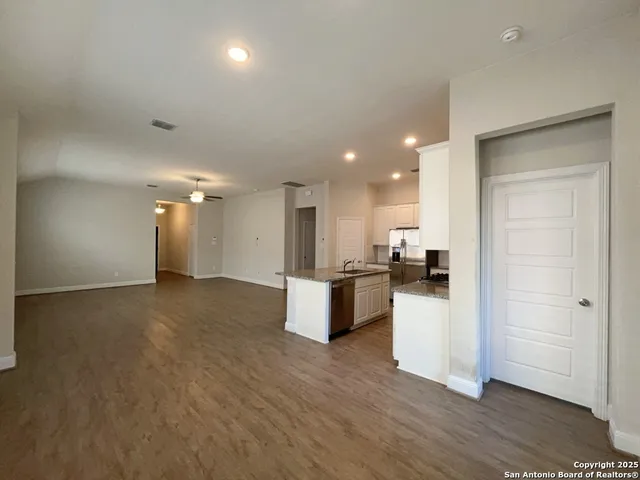 a kitchen with stainless steel appliances granite countertop a stove top oven a sink a refrigerator and white cabinets