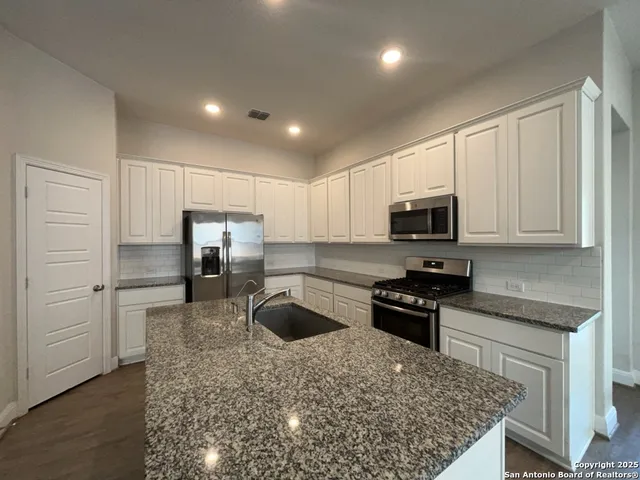 a kitchen with stainless steel appliances granite countertop white cabinets and black stove top oven with granite countertops