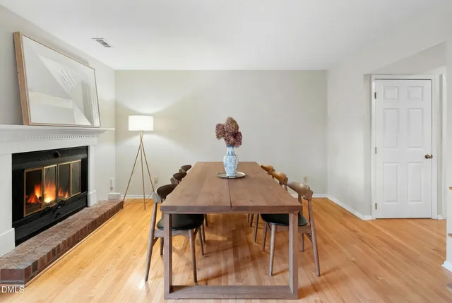 a dining room with a fireplace a chandelier and wooden floor