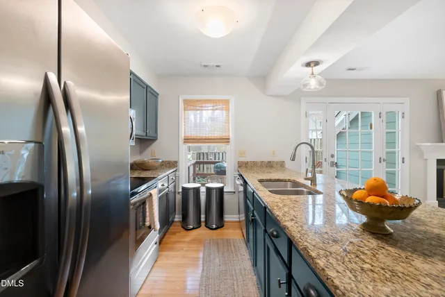 a kitchen with stainless steel appliances granite countertop a sink a stove and a refrigerator