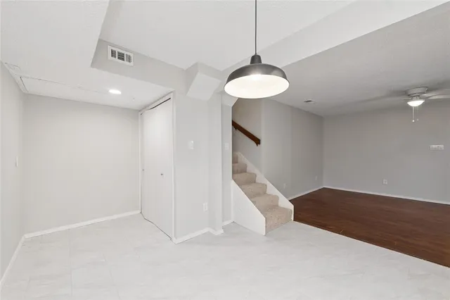 a view of an empty room with wooden floor and chandelier