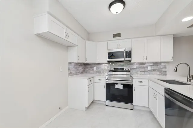 a kitchen with granite countertop white cabinets stainless steel appliances and a sink
