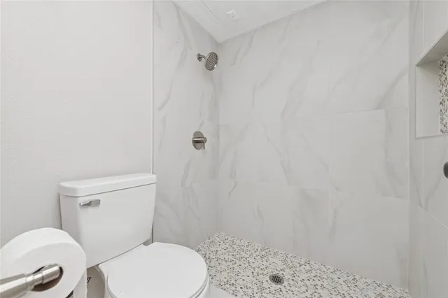 a white toilet sitting next to a shower