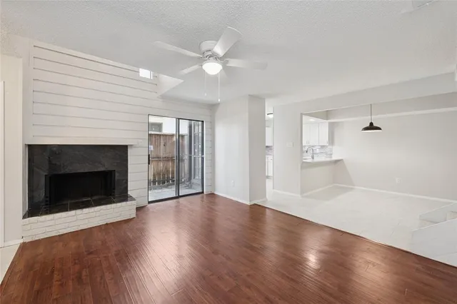 a view of an empty room with wooden floor fireplace and a window