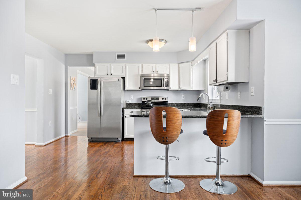 13534 King Charles Drive Chantilly, VA 20151 - Photo 2 of 28 a kitchen with stainless steel appliances granite countertop a stove a refrigerator a sink a microwave and a dining table with wooden floor