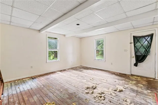 a view of an empty room with window and wooden floor