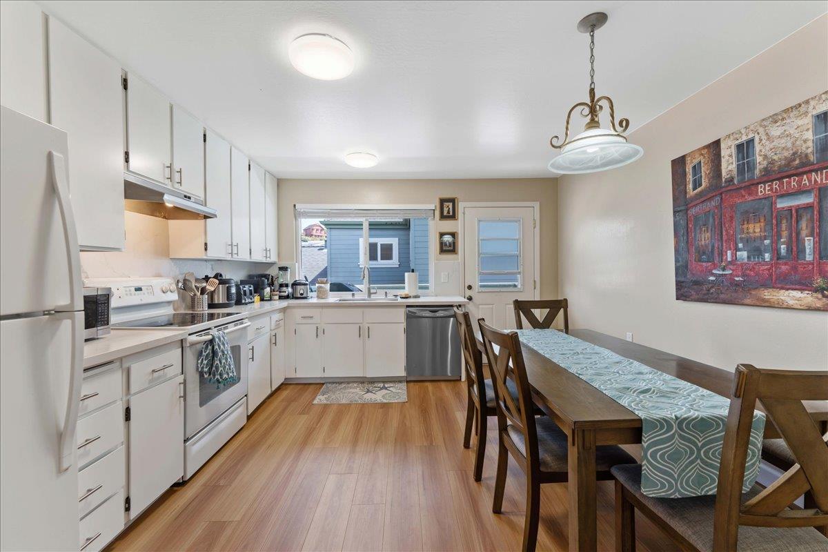 208 Stockton Avenue Capitola, CA 95010 - Photo 24 of 36 a kitchen with stainless steel appliances granite countertop a dining table chairs refrigerator and cabinets