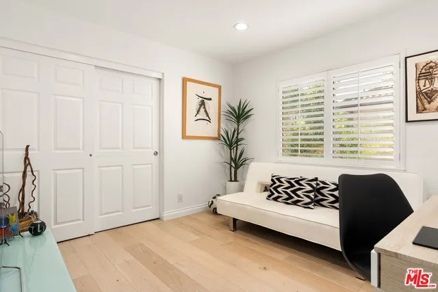 a bedroom with a bed and potted plant with two large window