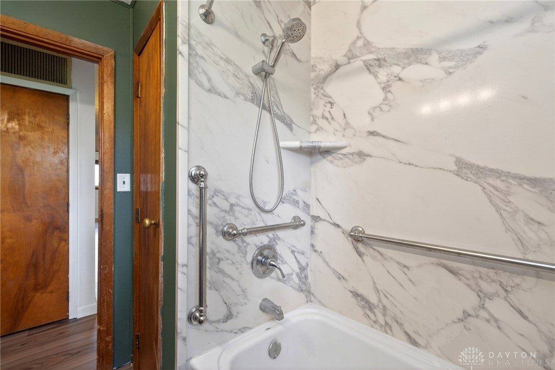 1005 Free Road New Carlisle, OH 45344 - Photo 31 of 43 This bathroom features a sleek tub with marble-patterned walls and convenient grab bars.
