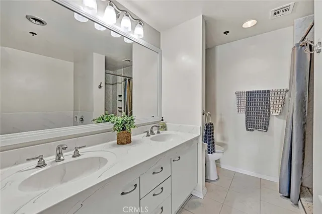 a bathroom with double vanity sink a mirror and a shower