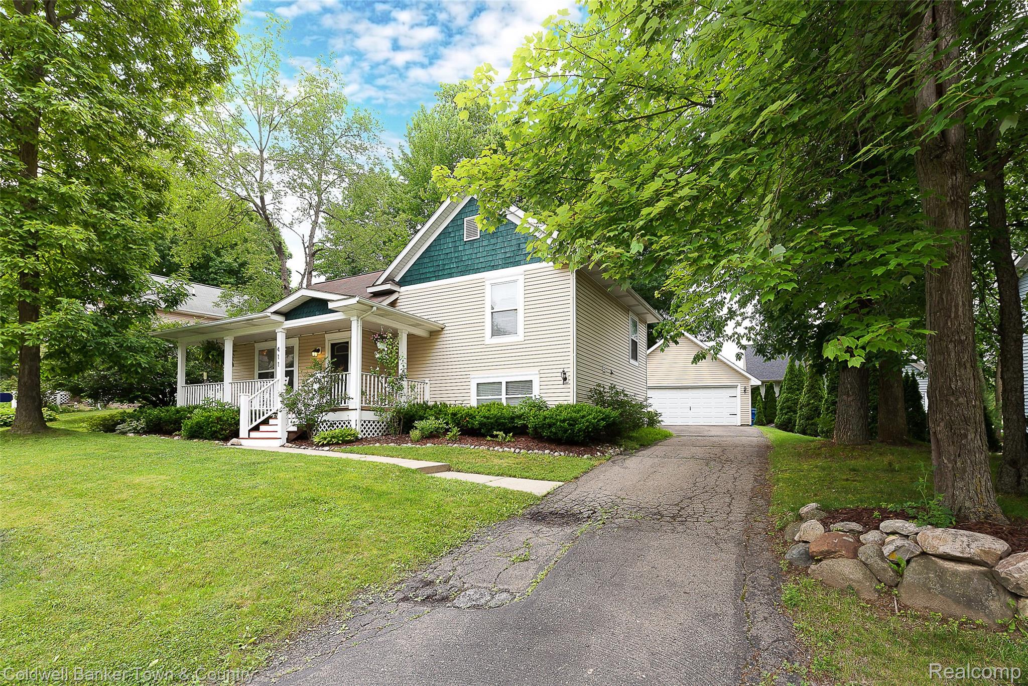 411 Springwell Lane Howell, MI 48843 - Photo 2 of 33 Exterior featuring a covered porch, light-toned siding, and a contrasting teal gable accent