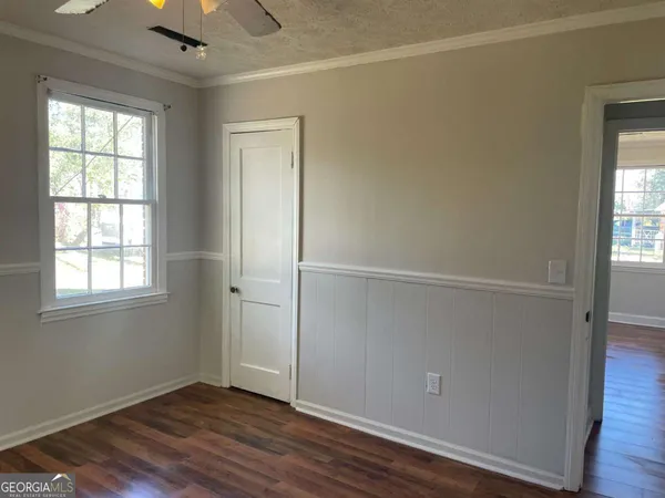 an empty room with wooden floor cabinet and windows