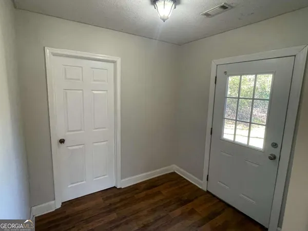 an empty room with wooden floor cabinet and windows