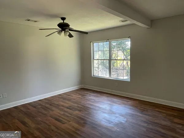 a view of an empty room with wooden floor and a window