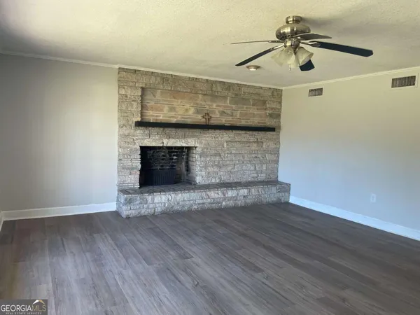 a view of an empty room with wooden floor and a fireplace