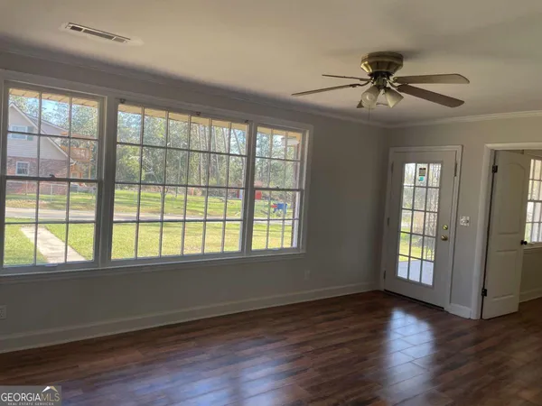a view of an empty room with wooden floor and a window