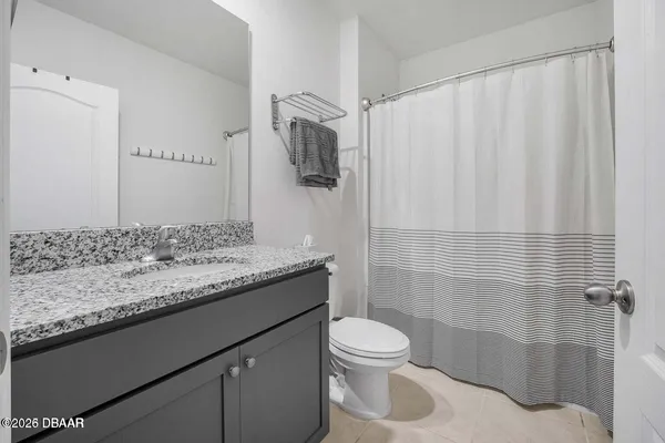 a bathroom with a granite countertop sink and a toilet