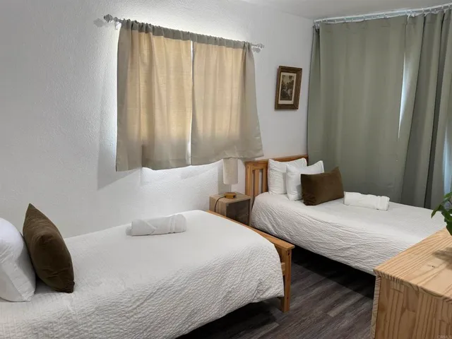 a bedroom with two beds and wooden floor