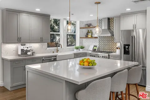 a kitchen with stainless steel appliances granite countertop a sink refrigerator and cabinets