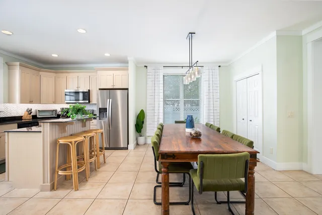 a kitchen with a dining table chairs and refrigerator