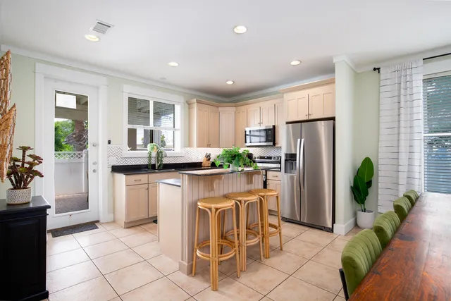 a kitchen with stainless steel appliances kitchen island granite countertop a refrigerator a stove a sink a dining table and chairs