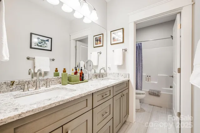 a bathroom with a granite countertop sink mirror and a toilet