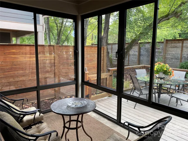 a living room with a table chair and a floor to ceiling window