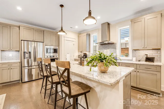 a kitchen with stainless steel appliances kitchen island granite countertop a dining table chairs and white cabinets