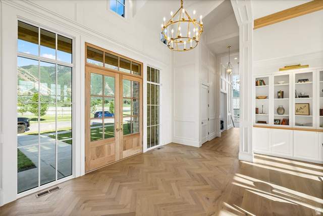 478 South Maple Lakes Drive Mapleton, UT 84664 - Photo 19 of 51 Grand entryway featuring double-door entry with transom windows, herringbone wood-finish flooring, and a large brass chandelier