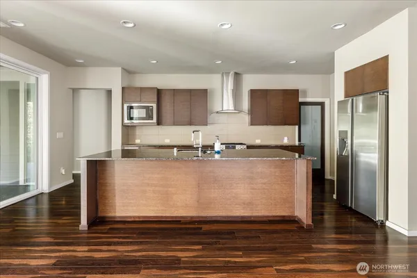 a large kitchen with stainless steel appliances granite countertop a refrigerator a stove and a sink