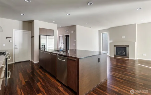 a kitchen with stainless steel appliances granite countertop a refrigerator a stove and a wooden floors