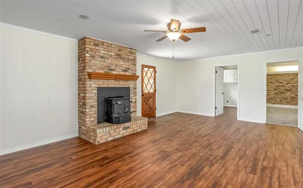 a view of an empty room with wooden floor fireplace and a window