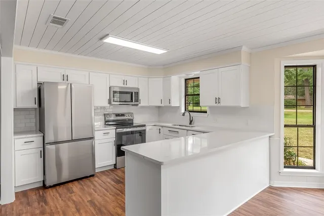 a kitchen with a refrigerator a stove top oven a sink and dishwasher with wooden floor