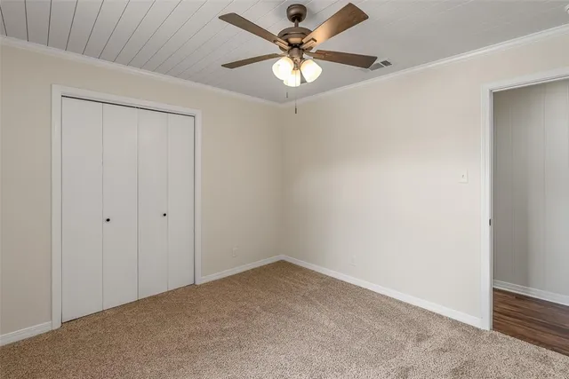 an empty room with a chandelier fan and windows