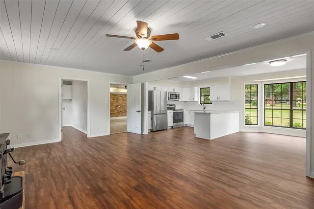 a view of an empty room with window and wooden floor