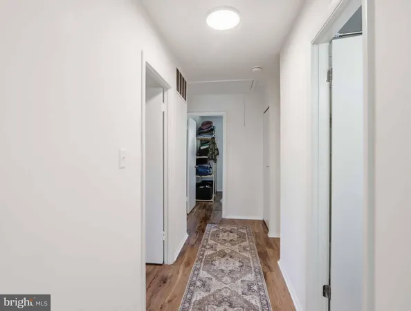 a view of a hallway with wooden floor and closet