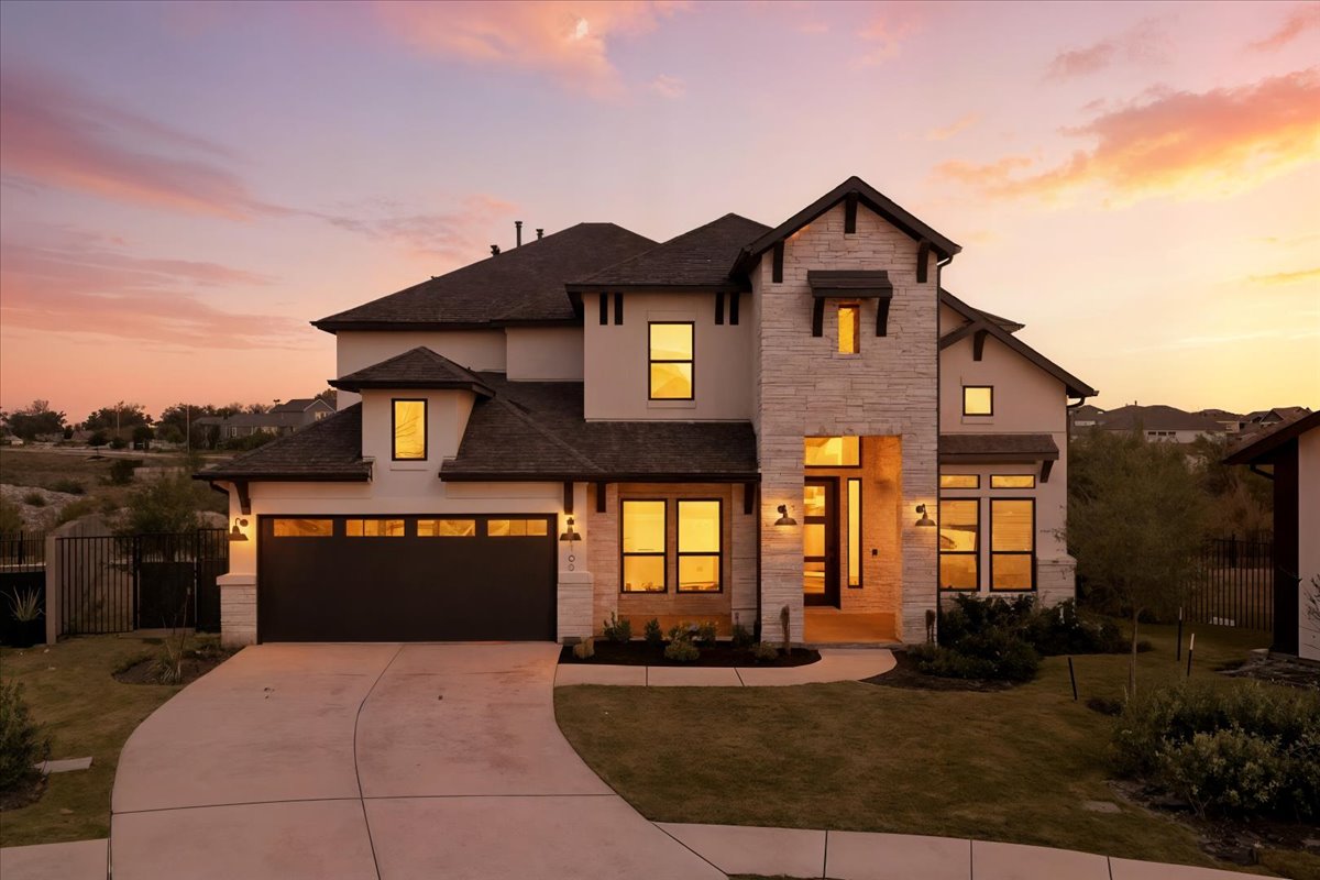 View of front of property featuring stone siding, driveway, stucco siding, and a shingled roof