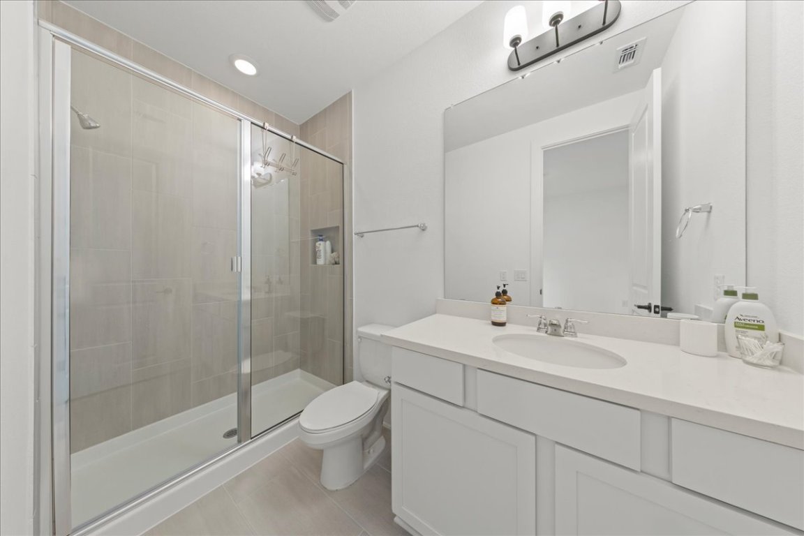 8700 Olmsted Way Austin, TX 78744 - Photo 24 of 40 Bathroom featuring a shower stall, light tile patterned floors, vanity, and recessed lighting