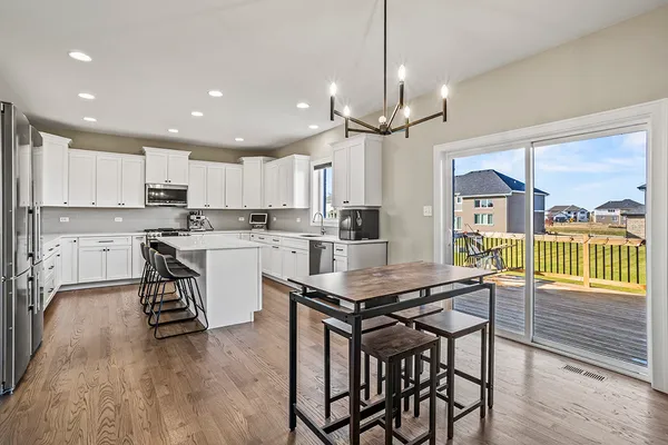 a kitchen with stainless steel appliances granite countertop a table chairs refrigerator and microwave