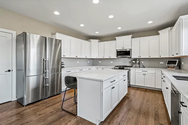 a kitchen with stainless steel appliances granite countertop a refrigerator sink and white cabinets