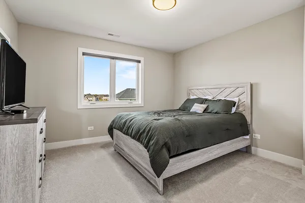 a bedroom with a bed and a flat tv screen on a dresser
