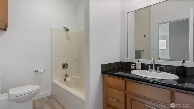 a bathroom with a granite countertop sink a toilet and shower