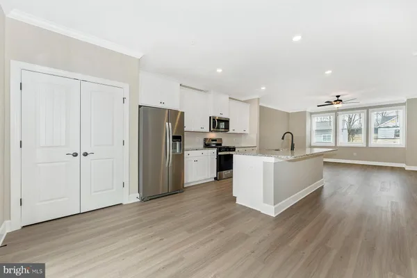 a large kitchen with a center island wooden floor stainless steel appliances and windows