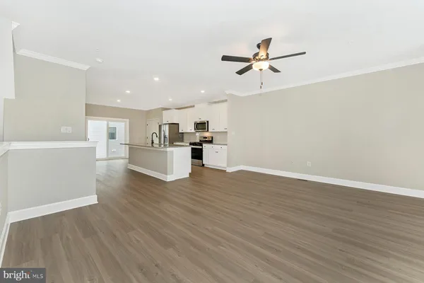 a view of a kitchen with wooden floor and a ceiling fan