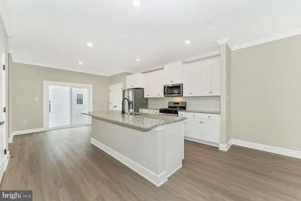 a kitchen with stainless steel appliances a sink stove and wooden floor