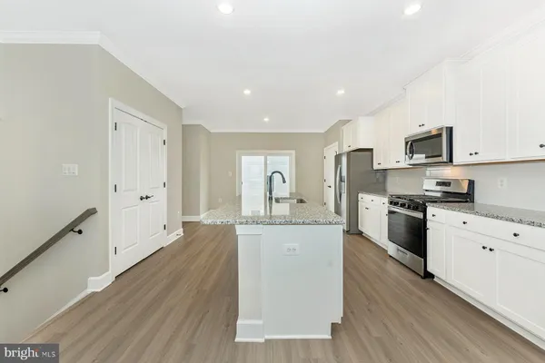 a large kitchen with granite countertop a stove top oven a sink a counter space and cabinets